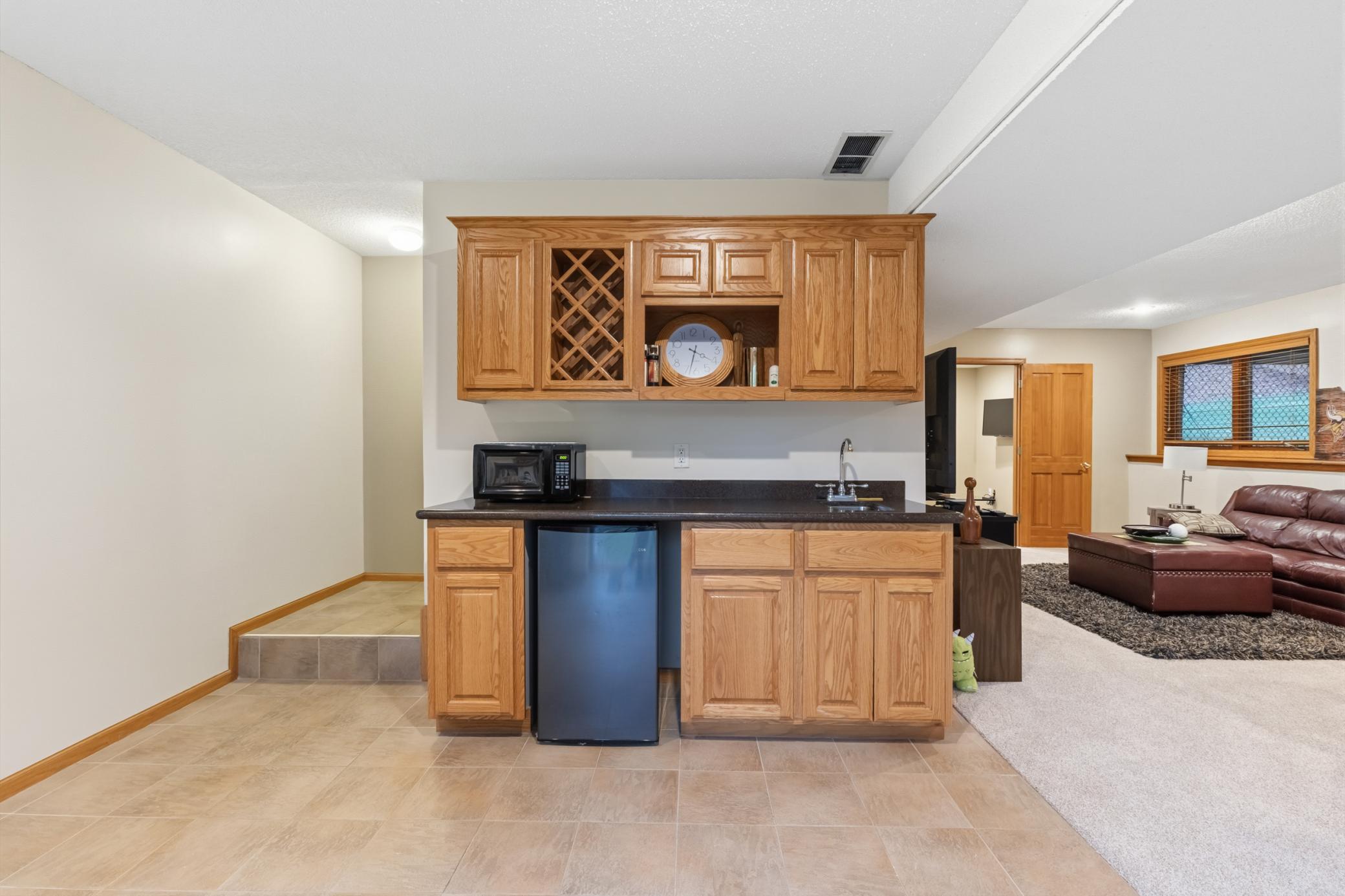 The basement's wet bar area. It has a small fridge and a sink, and lots of storage.