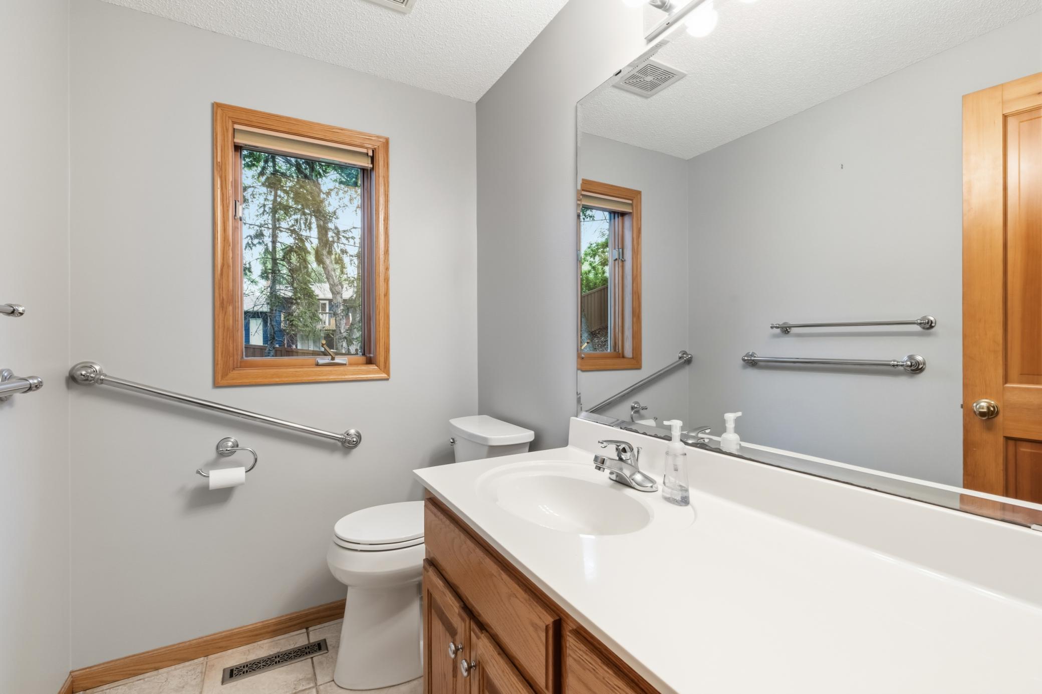 The half-bath/powder room in the main level with a window for natural light. With grab bar.