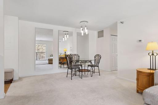 Bright and open living and dining space with neutral décor, modern lighting.
