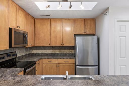 A view of the kitchen from the breakfast bar area. The closet on the right is a large walk-in closet. Skylight brings in great natural light.