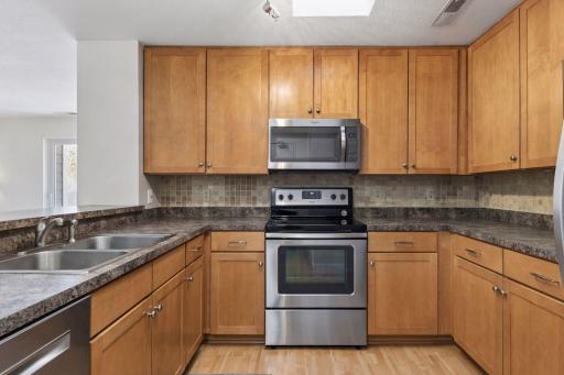 Well-appointed kitchen featuring warm wood cabinetry, stainless steel appliances, tiled backsplash, and ample counter space for cooking and meal preparation.