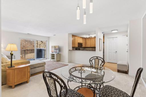 Open-concept living and dining area with neutral finishes, modern lighting, and easy flow to the kitchen and living room. Sliding glass doors lead to the private deck overlooking peaceful wooded views.
