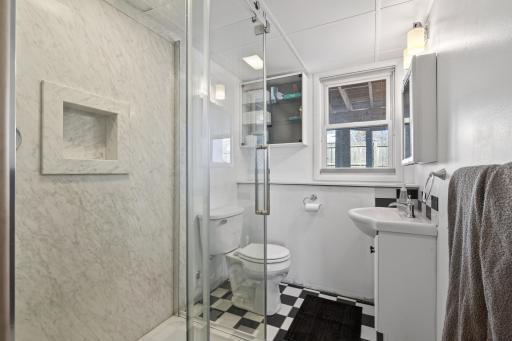 Bathroom 2 (lower level) features walk-in glass shower and retro tile