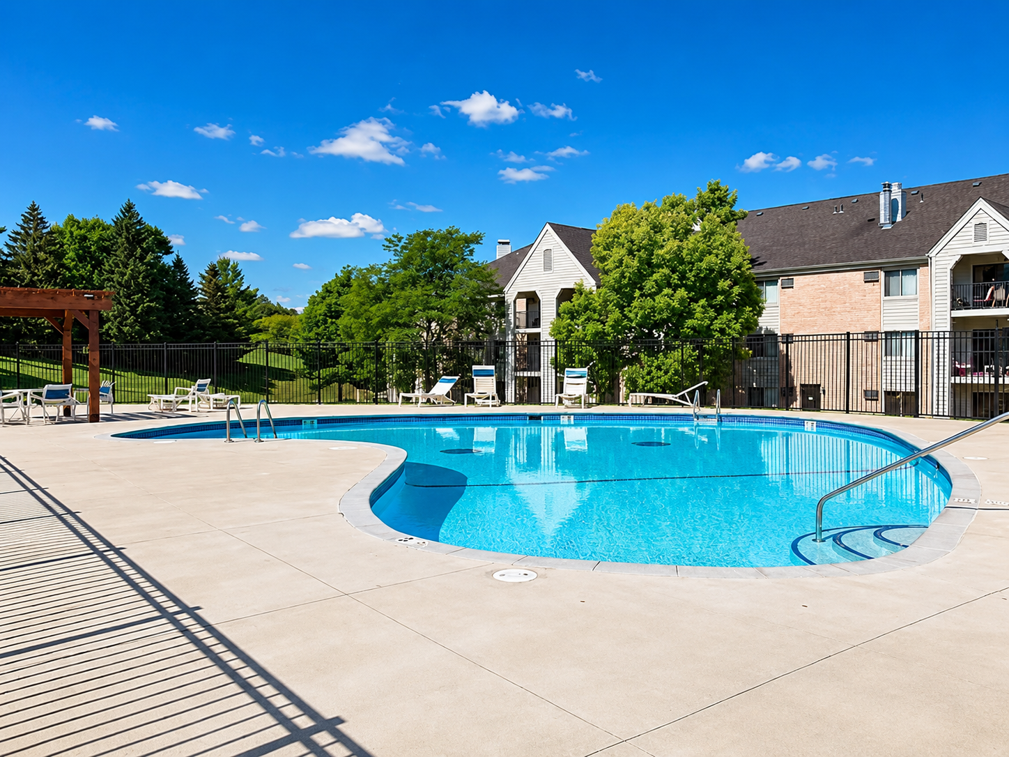 Enjoy resort-style living with access to the sparkling community outdoor pool, complete with a sprawling concrete sundeck, lounge seating, and a secure perimeter fence.