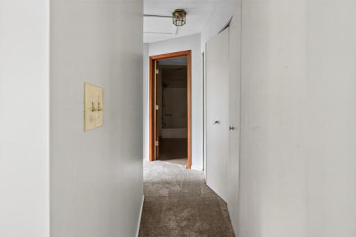 A neutral, carpeted hallway with a handy double-door closet connects the main living spaces to the private bedrooms and bath.