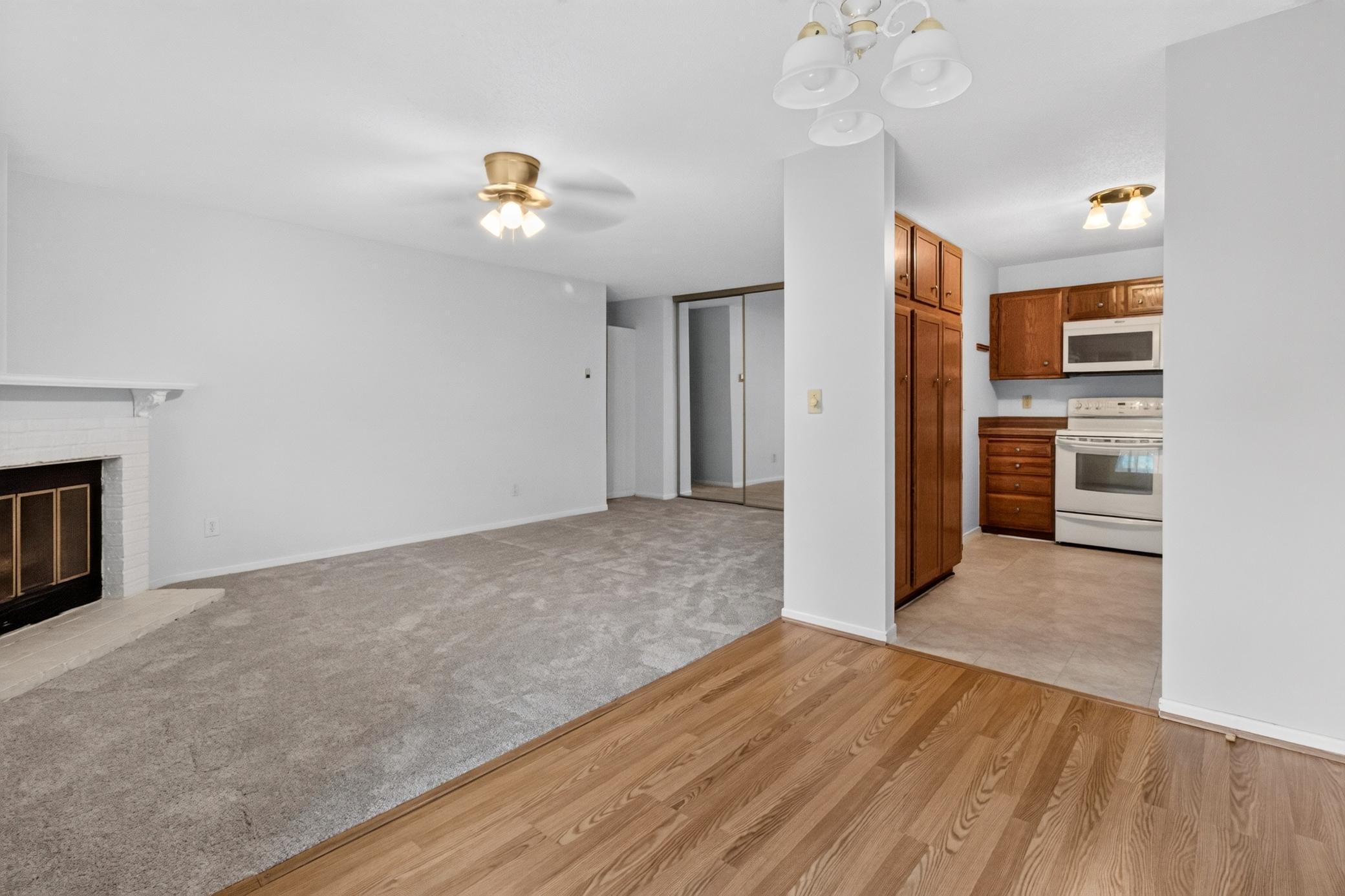 Bright and airy open-concept living space featuring a cozy fireplace, classic ceiling fan, and seamless transition into the dining area and kitchen—perfect for entertaining.