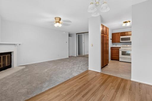 Bright and airy open-concept living space featuring a cozy fireplace, classic ceiling fan, and seamless transition into the dining area and kitchenâperfect for entertaining.