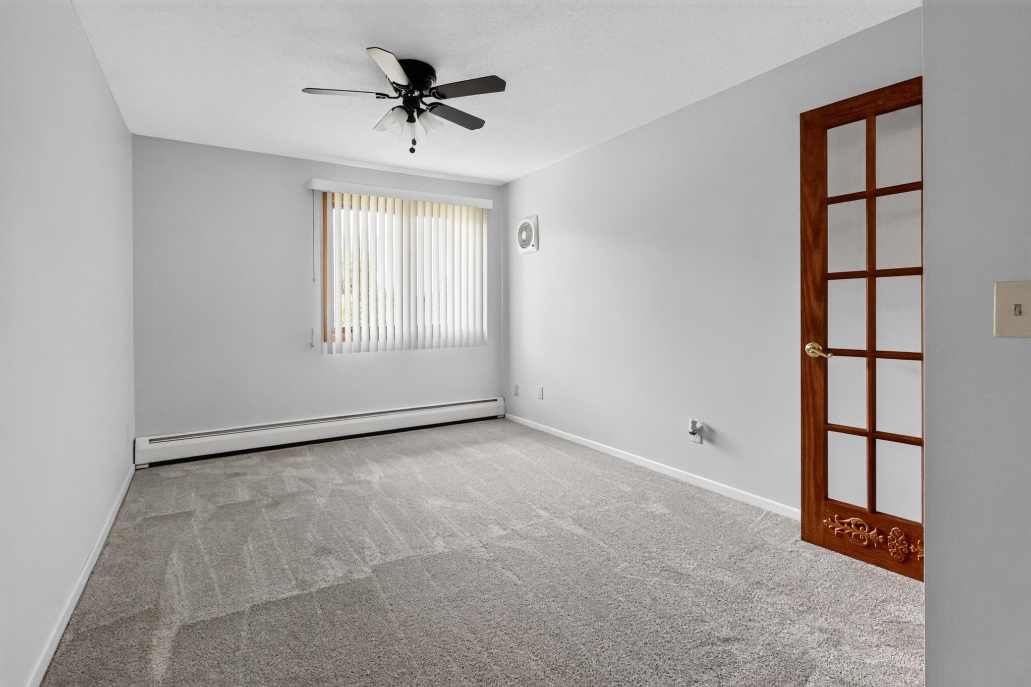 Another spacious bedroom offering neutral tones, ample closet space, and a charming glass-paneled French door leading into the main living areas.