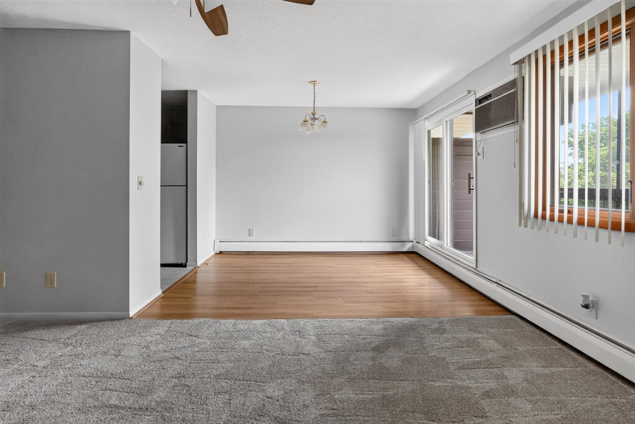 The open-concept dining area showcases beautiful wood-look flooring and a classic chandelier fixture, directly adjacent to large sliding glass doors that open up to a private balcony space.