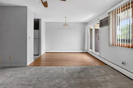 The open-concept dining area showcases beautiful wood-look flooring and a classic chandelier fixture, directly adjacent to large sliding glass doors that open up to a private balcony space.