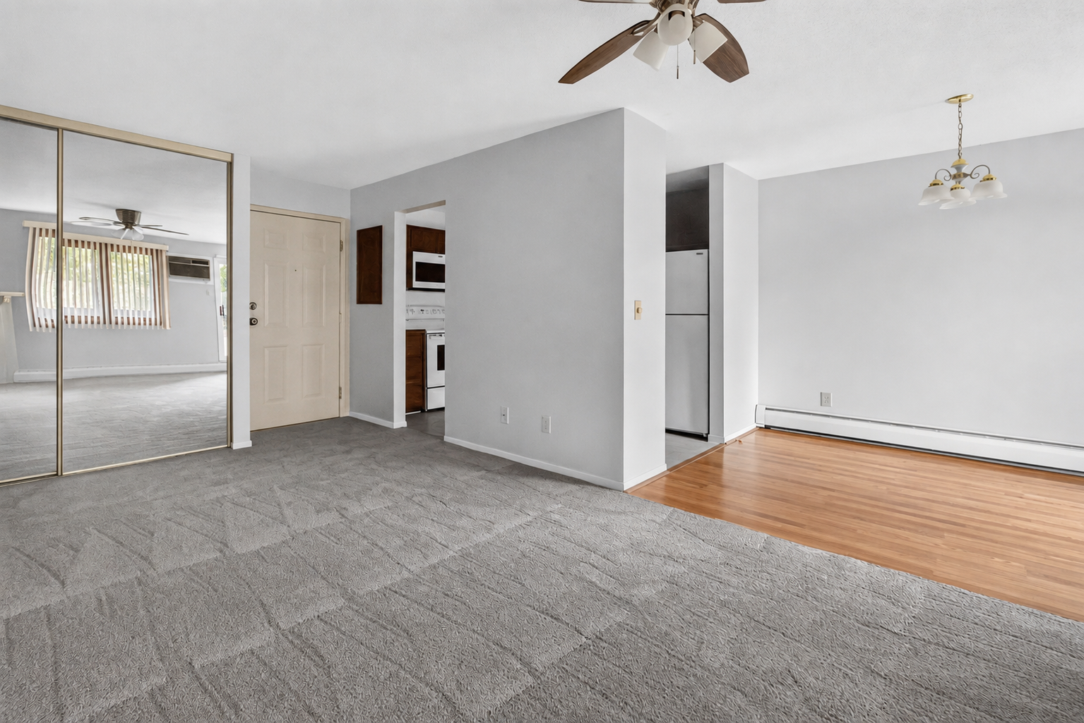 Welcome home to an inviting open-concept floor plan featuring cozy carpeting in the living area, a ceiling fan, and a seamless transition to the bright dining room with wood-look flooring.