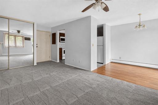 Welcome home to an inviting open-concept floor plan featuring cozy carpeting in the living area, a ceiling fan, and a seamless transition to the bright dining room with wood-look flooring.