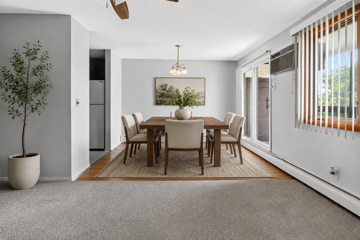 The open-concept dining area showcases beautiful wood-look flooring and a classic chandelier fixture, directly adjacent to large sliding glass doors that open up to a private balcony space.
