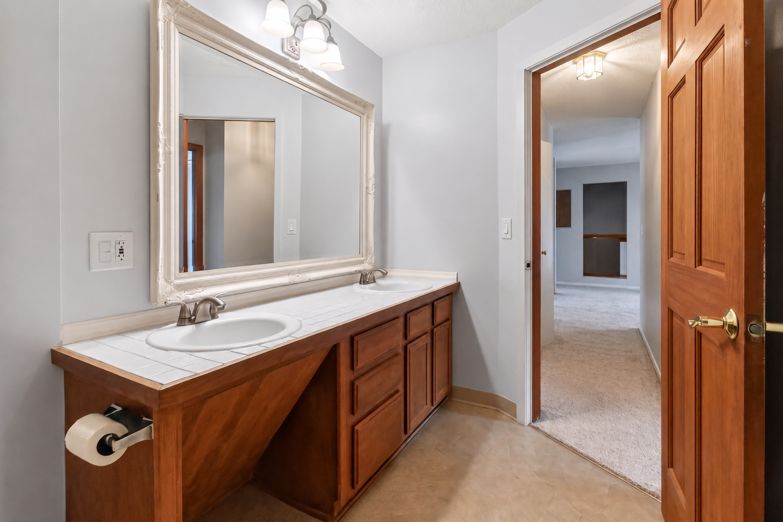 The bathroom's double-sink layout provides plenty of counter space and under-vanity storage, perfectly positioned right off the main hallway.
