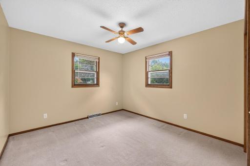 Comfortable main-level bedroom with two windows and a ceiling fan for added comfort.