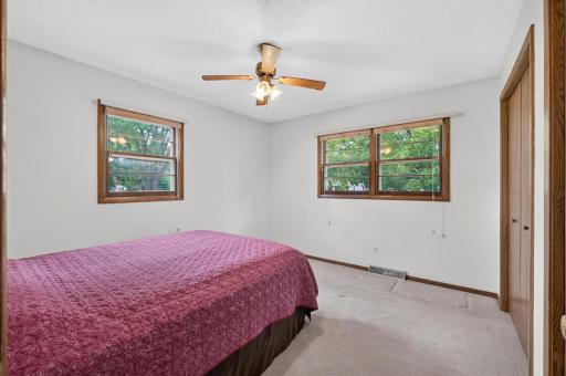 A second main-floor bedroom features multiple windows and a ceiling fan.
