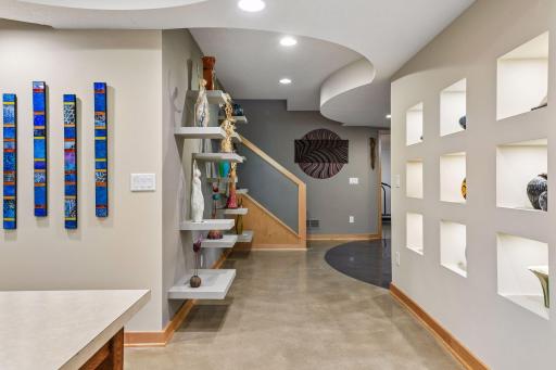 Curved walls and custom display shelving add architectural interest throughout the lower level.