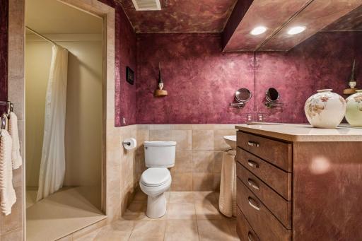 Warm finishes, generous vanity storage, and a walk-in shower complete the bathroom.