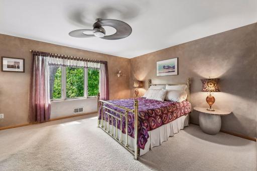 The spacious main-level primary bedroom offers a peaceful retreat with tree views.