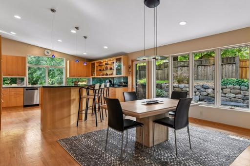 The kitchen flows seamlessly into a light-filled dining area overlooking the greenery.