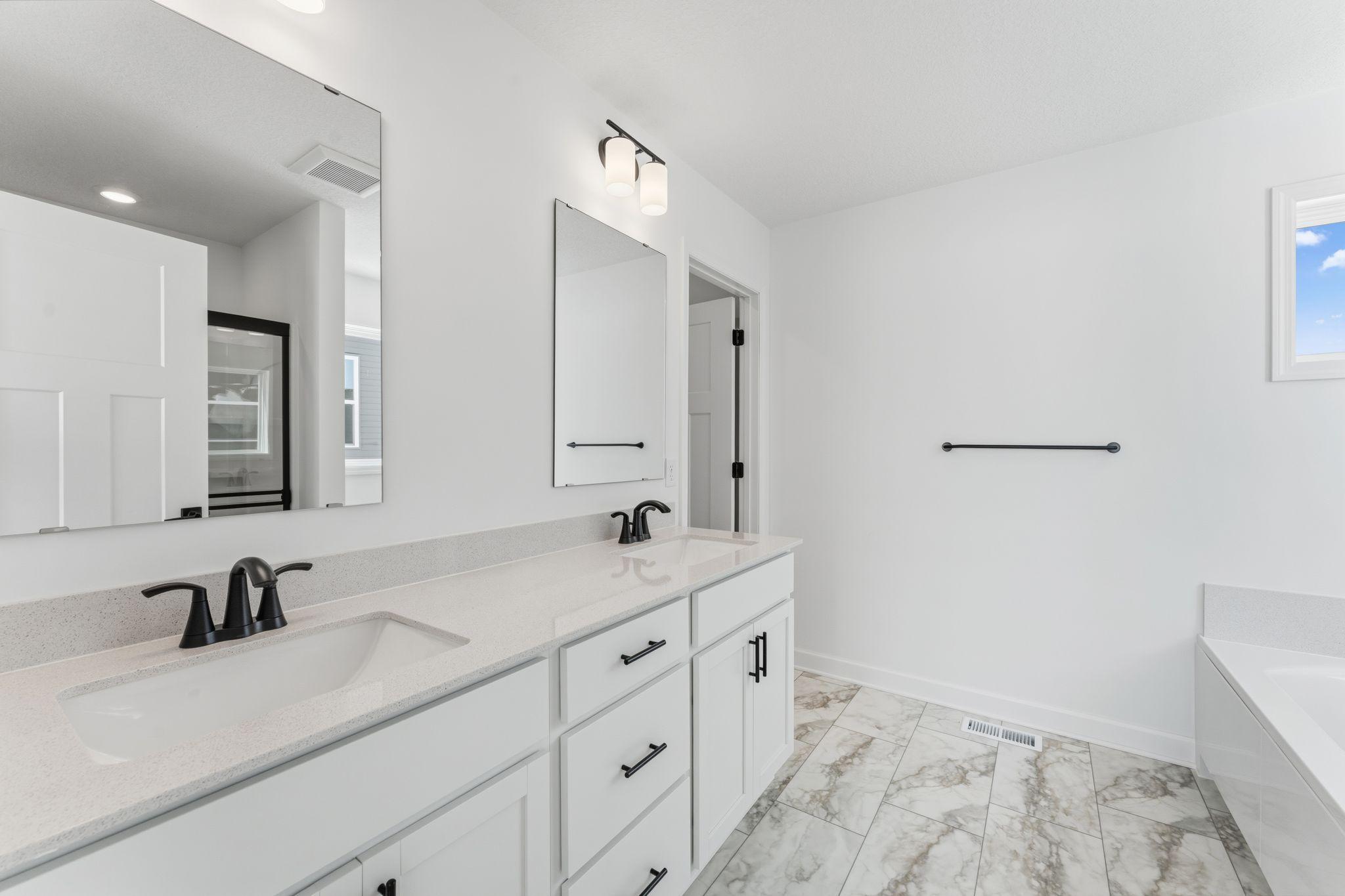 Quartz countertops, plate-glass mirrors, raised-height cabinets and Moen® Glyde faucets unite at this oversized vanity
