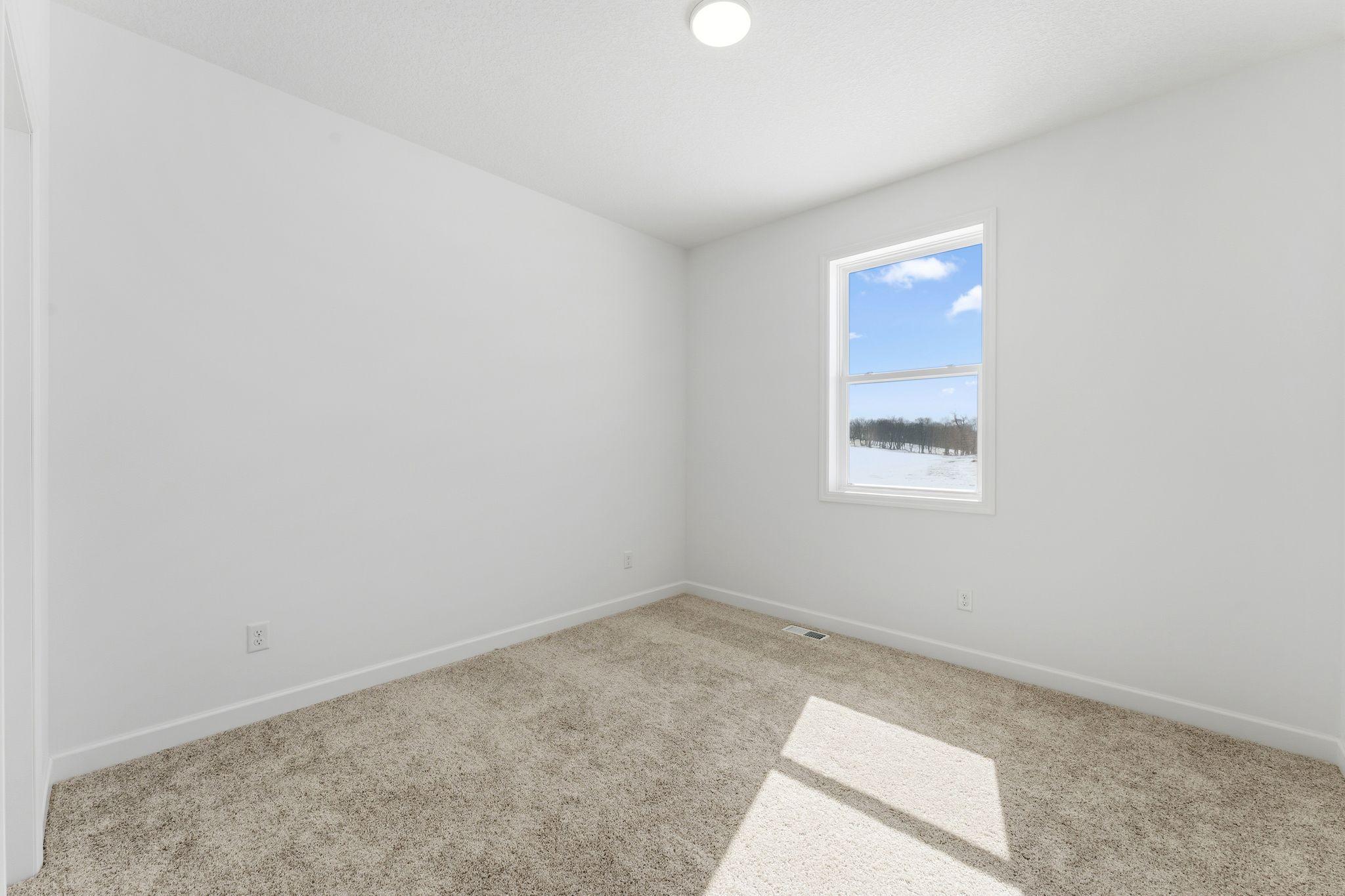 Tucked into the corner of the home, this secondary bedroom is sequestered from the rest of the first floor living spaces, creating a private environment ideal for overnight guests.