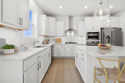 (Photo of similar home, finishes will vary) The stunning kitchen features a large center island, quartz countertops, LVP floors, stainless appliances and more.