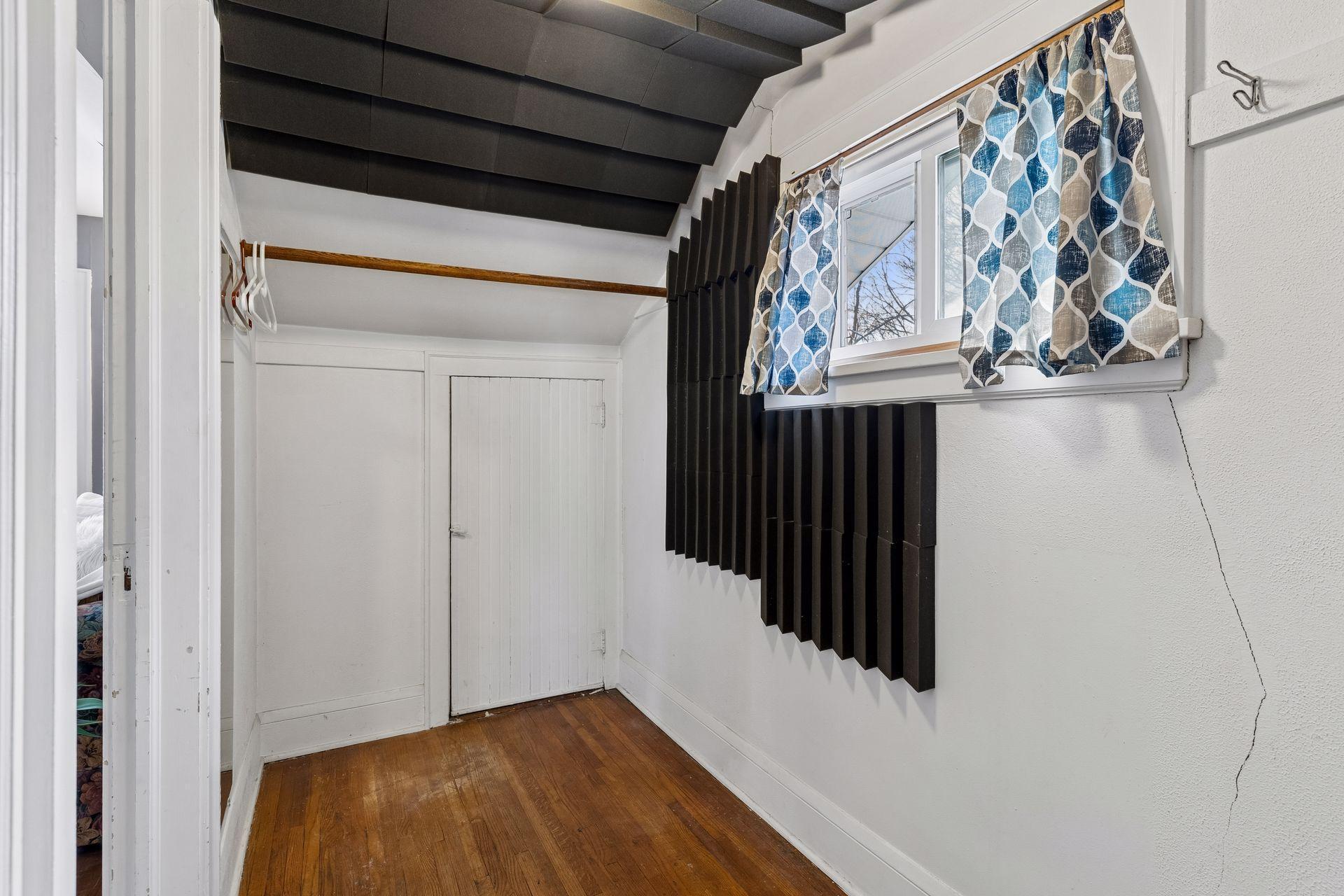 Walkthrough closet has front window, hanging rods on both sides and closet storage on both sides.