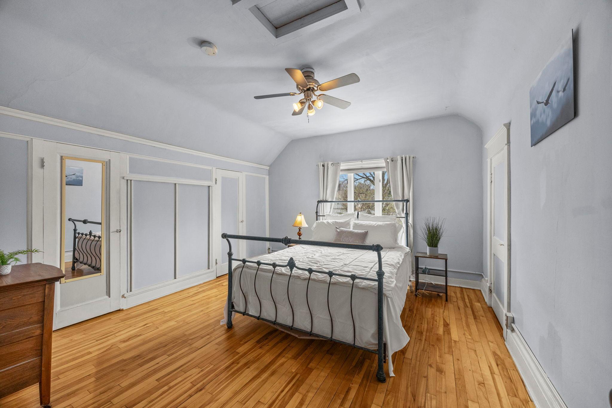 Large primary bedroom has TONS of storage in the full wall of closets. This room is so lovely and charming, with white woodwork and gorgeous wood floors.