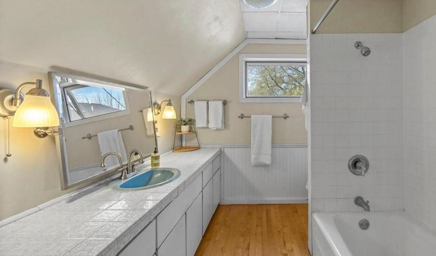 Spacious bathroom has brushed nickel hardware and white wainscoting.