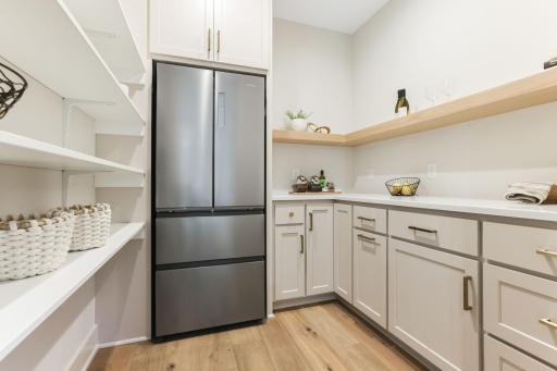 The walk-in pantry offers exceptional storage and convenience, complete with a full-size refrigerator, ample counter space and shelving to keep everything organized.