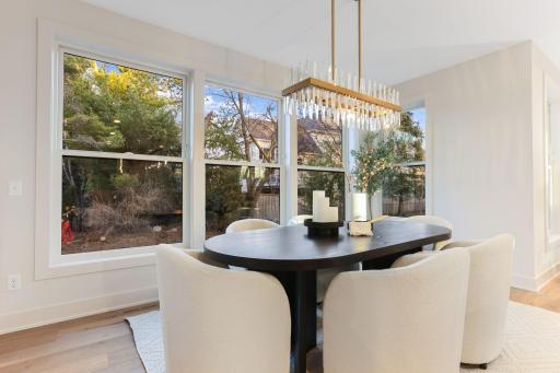 The dining room features expansive windows that flood the main floor with natural light, enhancing the open, airy feel while seamlessly connecting it to the surrounding living spaces.