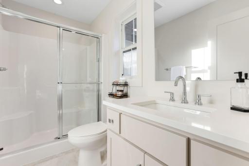 This private Â¾ bathroom features a sleek quartz vanity, offering both style and functionality.