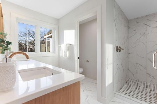It features a sleek quartz vanity, seamlessly blending modern elegance throughout the home.