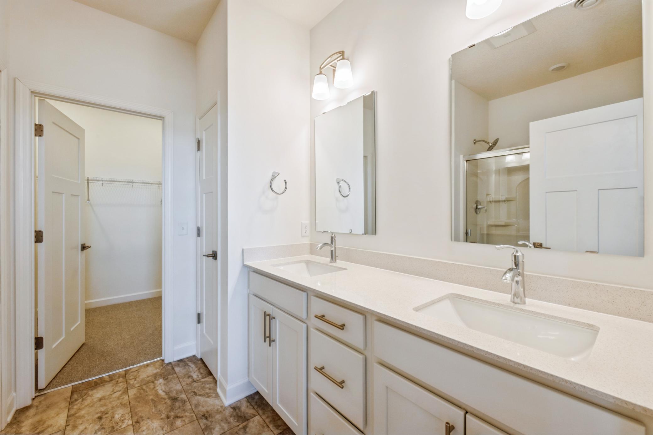 (Photo of a similar home, actual finishes may vary) Quartz-topped dual undermount sinks with Moen® faucets in the spa-inspired owner’s suite bathroom