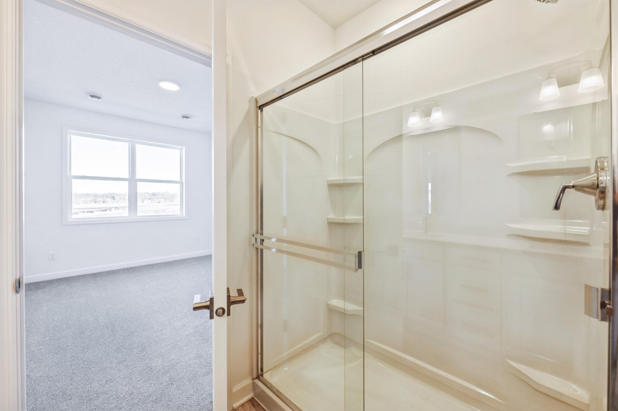 (Photo of a similar home, actual finishes may vary) Enjoy easy access to a glass-enclosed shower