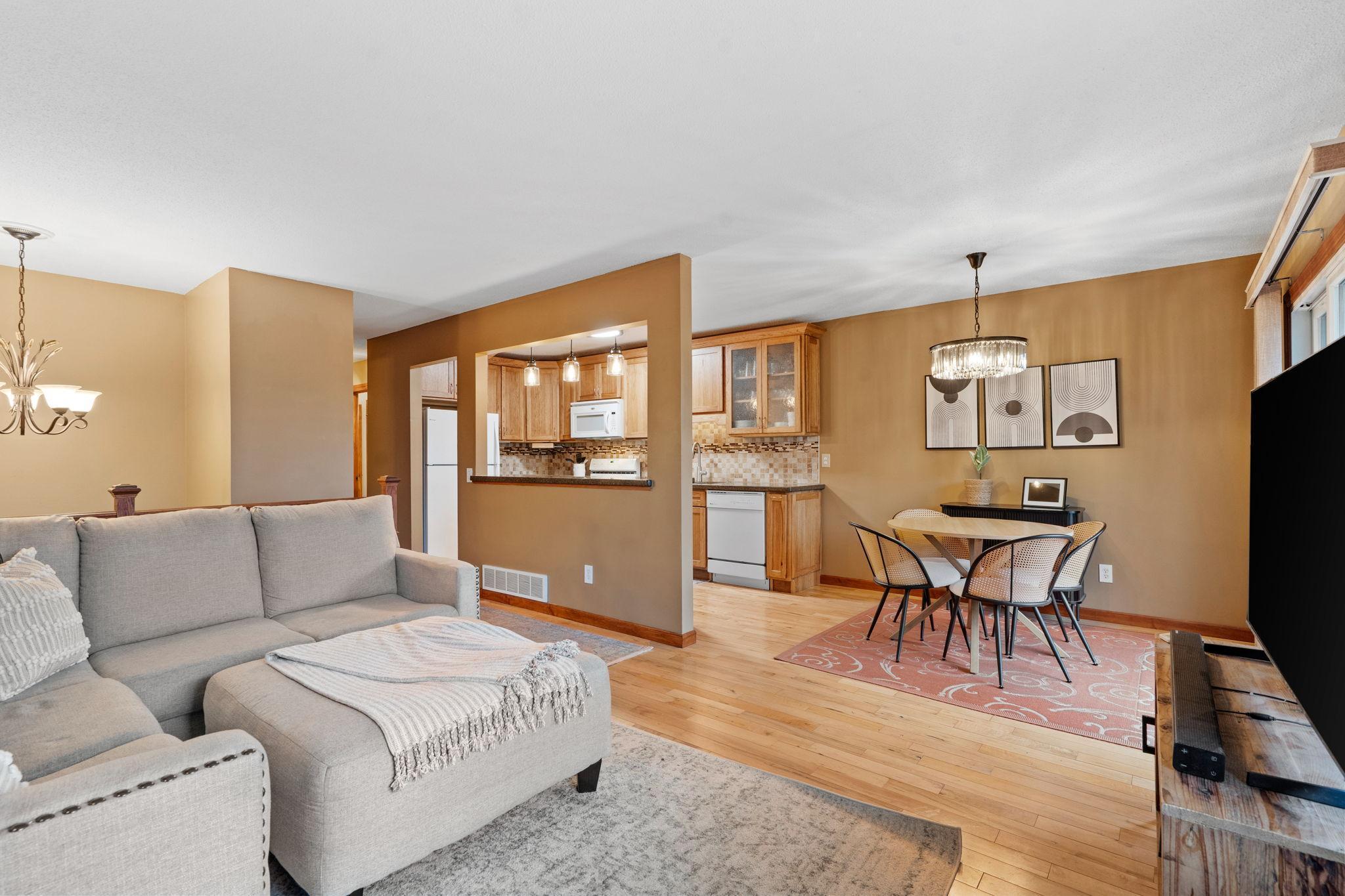 Well-lit open floorpan with updated light fixtures and hardwood floors
