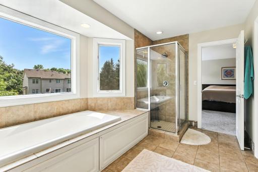 Primary suite bathroom with bay windows, soaking tub, and walk-in shower