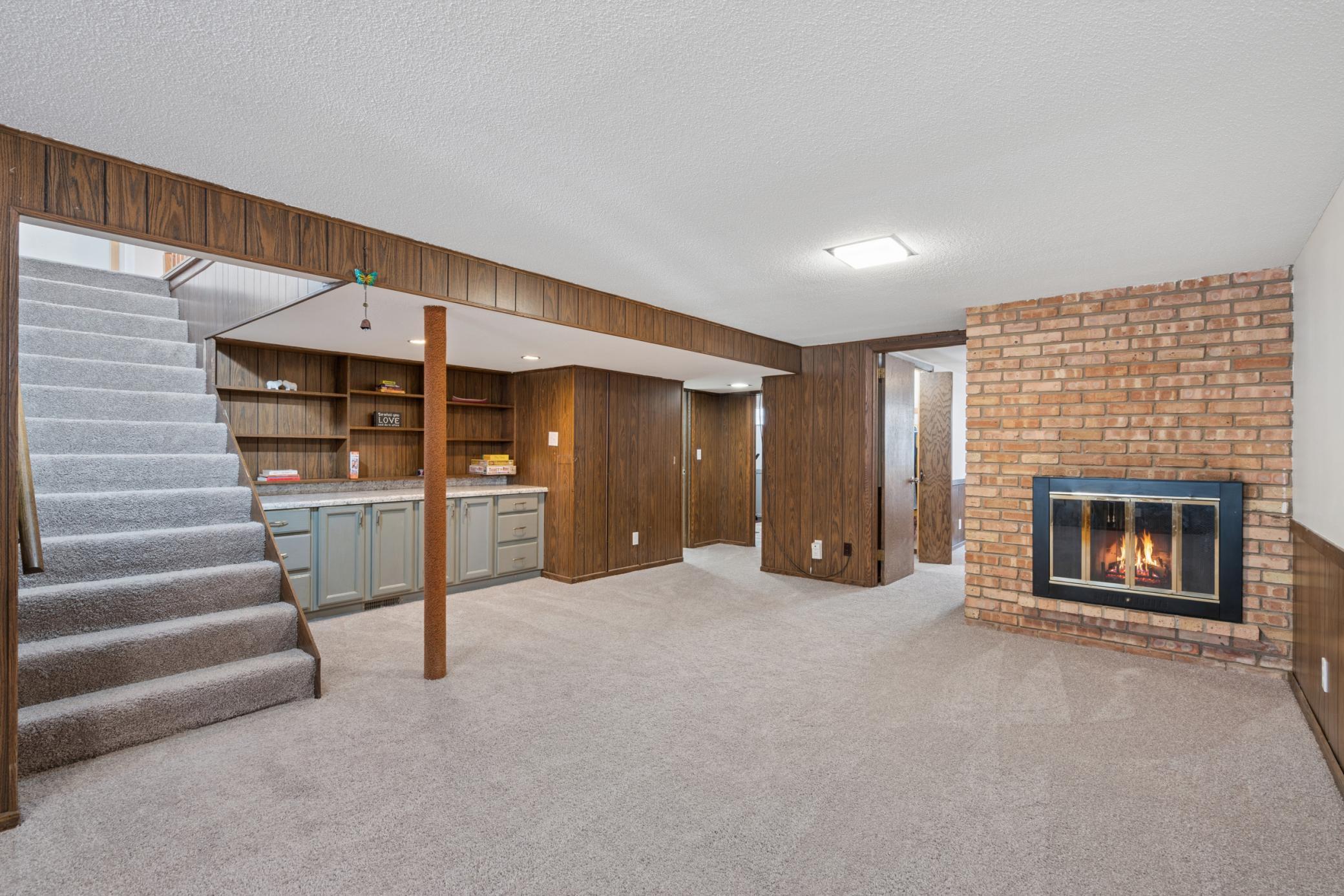 Large and functional lower-level family room with new carpet, wood-burning fireplace, and built-ins