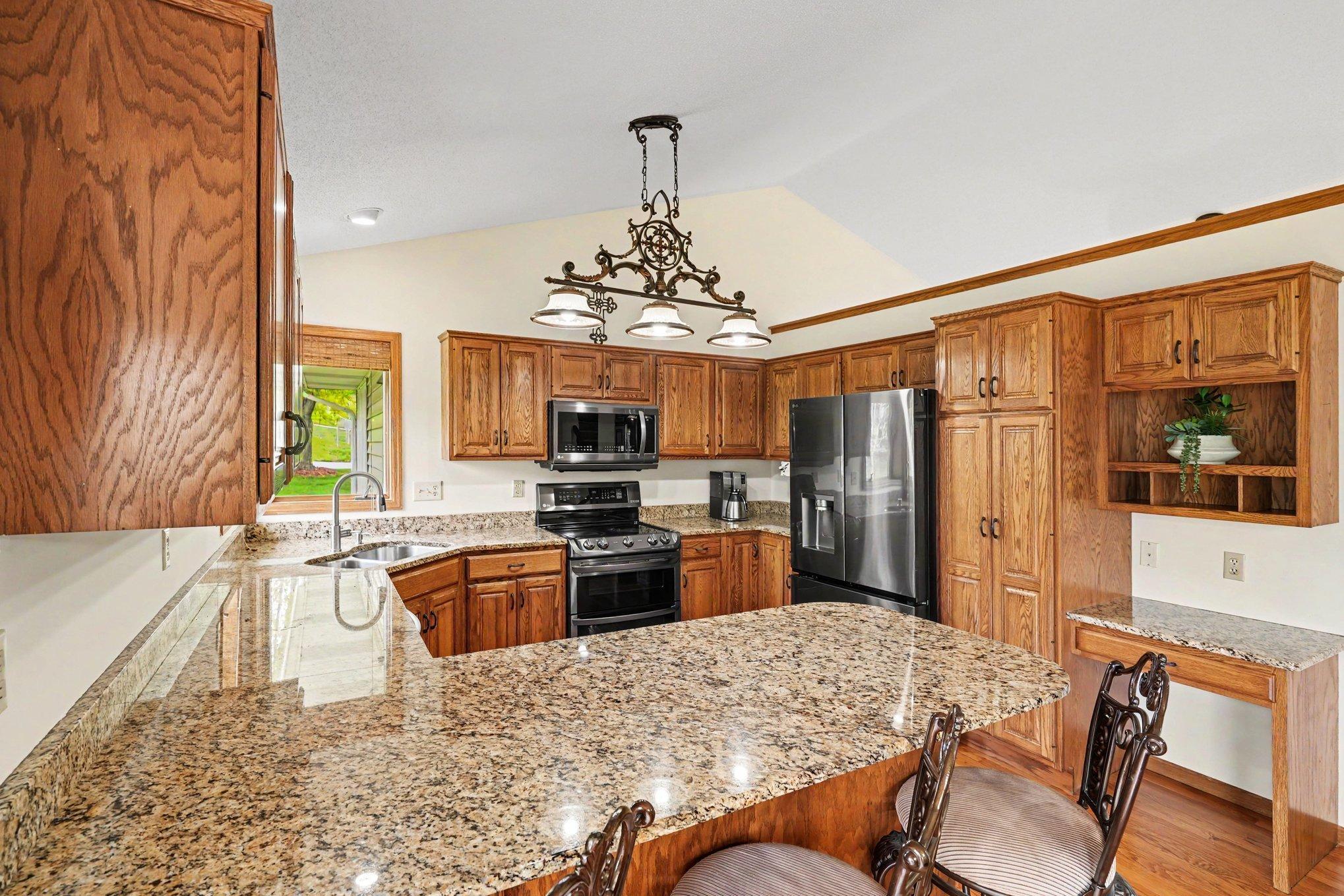 The spacious kitchen shines with gunmetal stainless steel appliances, granite countertops, & double sinks w/disposal. Corner windows flood the space with natural light while offering lovely views. Functional, stylish, & perfect for the home chef!