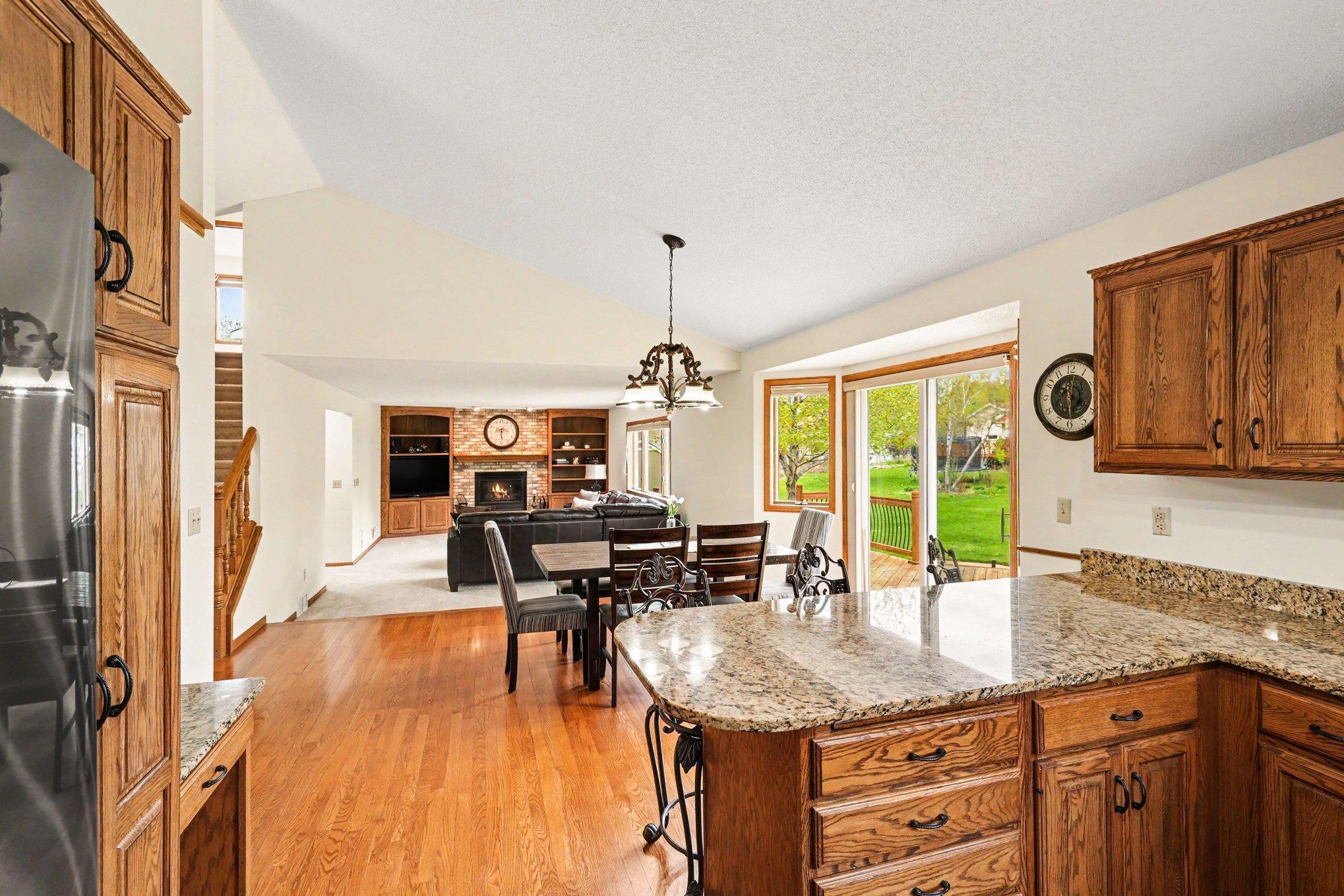 Featuring beautiful oak cabinetry and a peninsula breakfast bar, this kitchen is designed for gathering. This view showcases the seamless open layout & stunning hardwood floors.