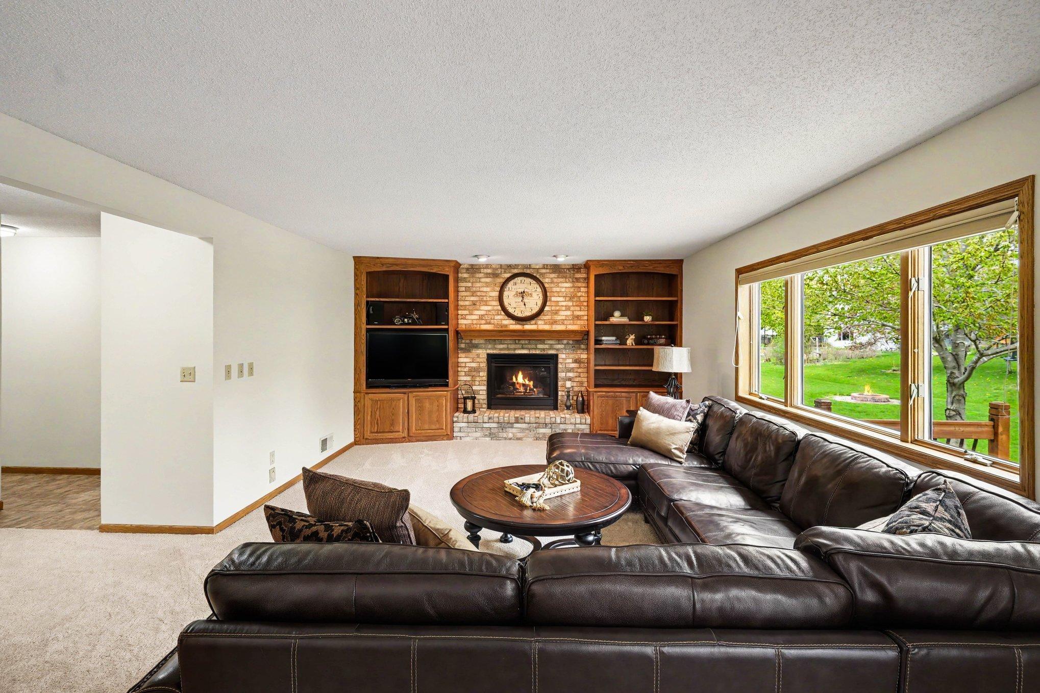 Filled with natural light from a large window, the main floor living room features brand new carpet and built-in bookcases. A classic brick gas fireplace anchors the space, creating a cozy, inviting atmosphere.