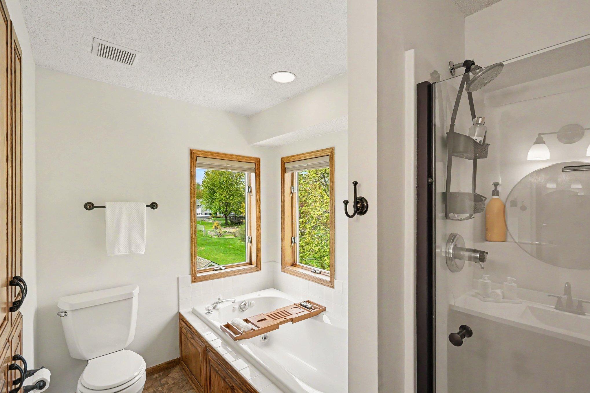 This spa-like private bath features a jetted soaking tub, a glass-door shower, and a deep linen closet. Corner windows flood the space with light, while top-down/bottom-up blinds offer the perfect balance of sunshine and privacy.