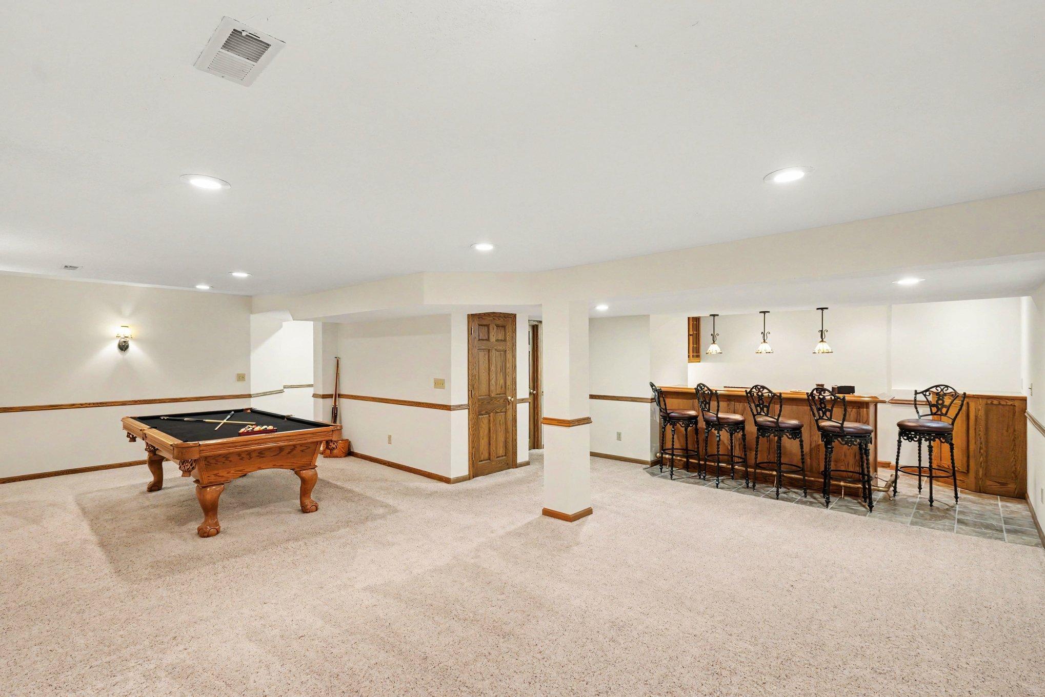 The lower-level family room is an entertainer's dream! This massive $35' \times 21'$ space is incredibly versatile, featuring a built-in wet bar, designer lighting, under-stairs storage, and a convenient 3/4 bath. Perfect for any lifestyle!