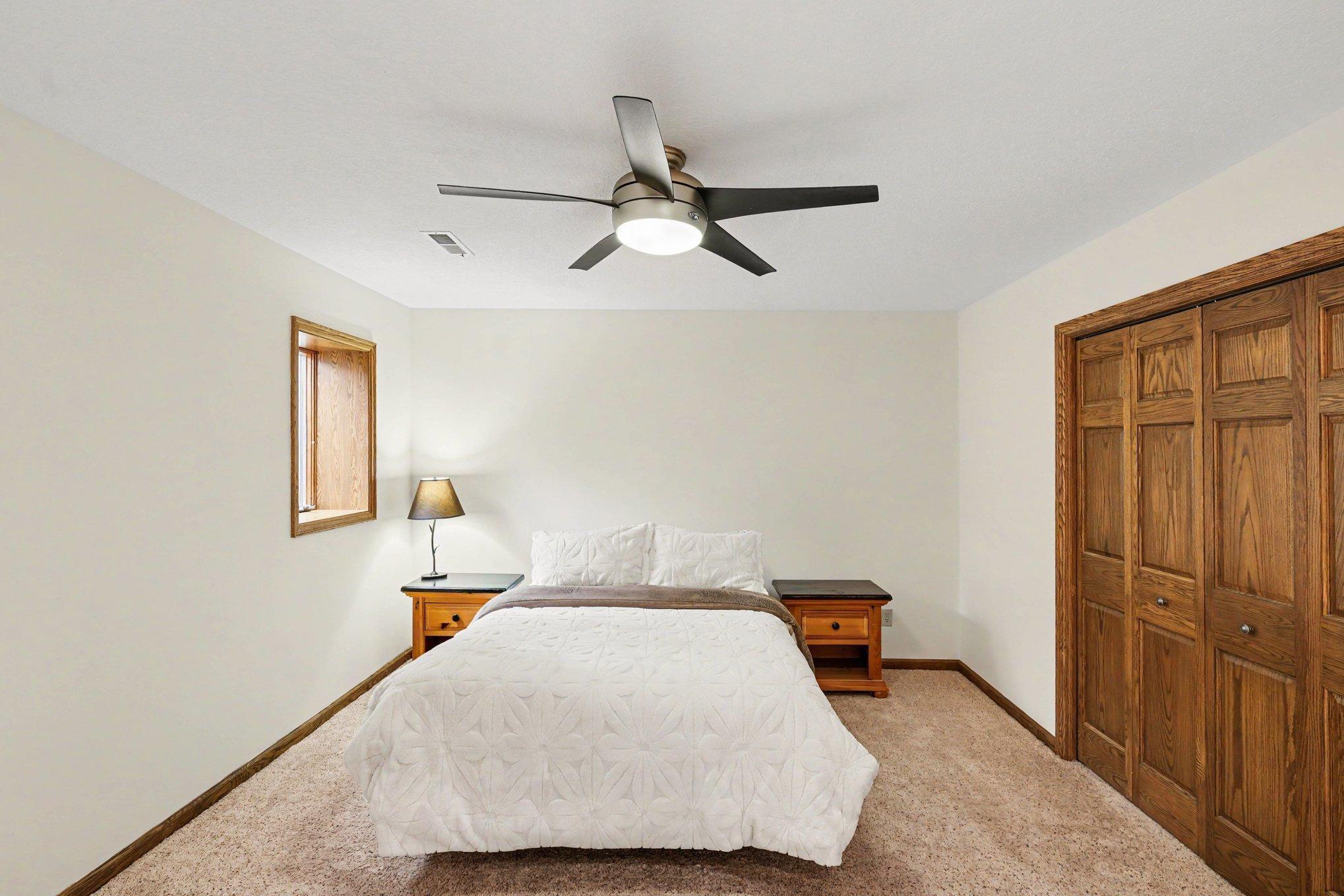 The lower-level fourth bedroom is a quiet, comfortable retreat. It features a spacious closet, a ceiling fan for year-round comfort, and a large egress window that ensures the space is safe and filled with natural light.