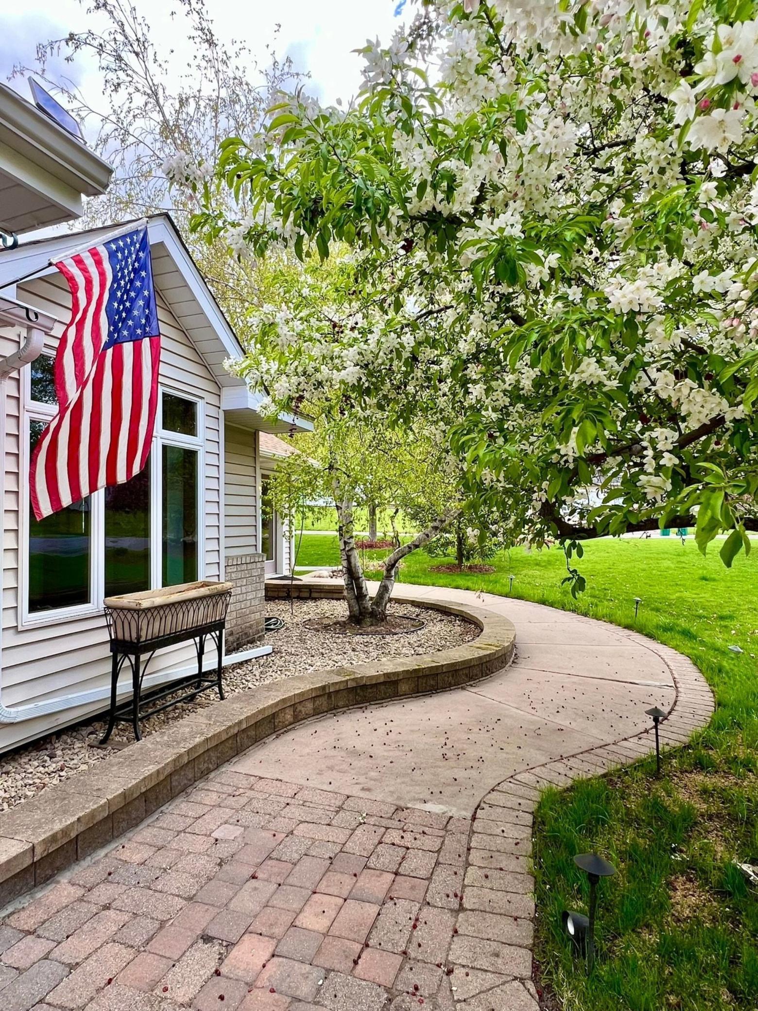 A charming front walkway leads directly to the sunroom's private entrance. Surrounded by flowering trees and mature landscaping, this spacious corner lot offers a park-like atmosphere right at home.