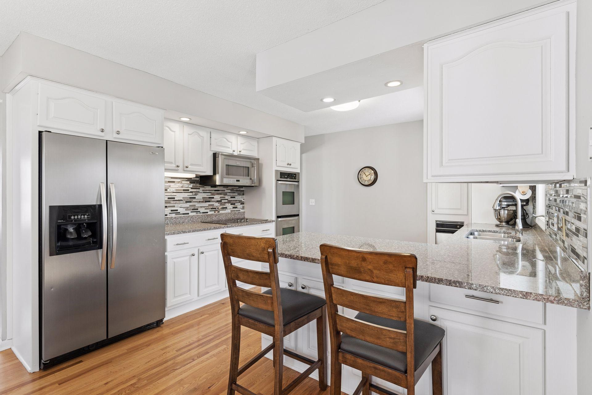 Crisp and clean kitchen with painted white cabinetry, stainless appliances, and breakfast bar.