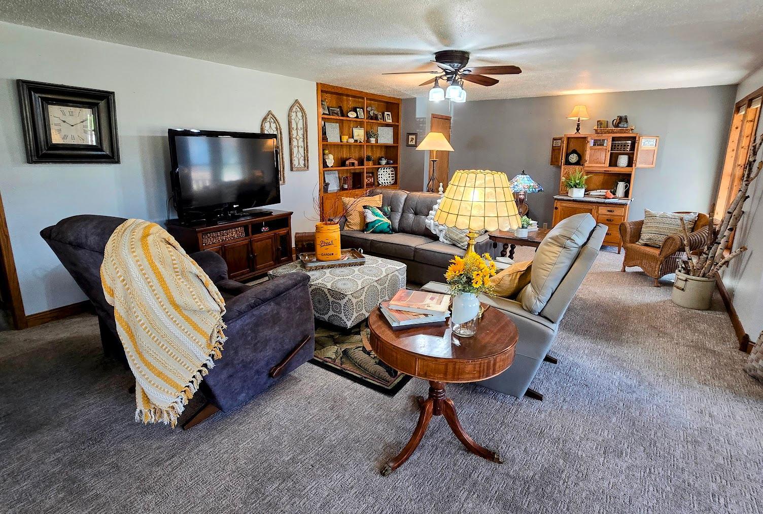 Spacious carpeted living room with ceiling fan.