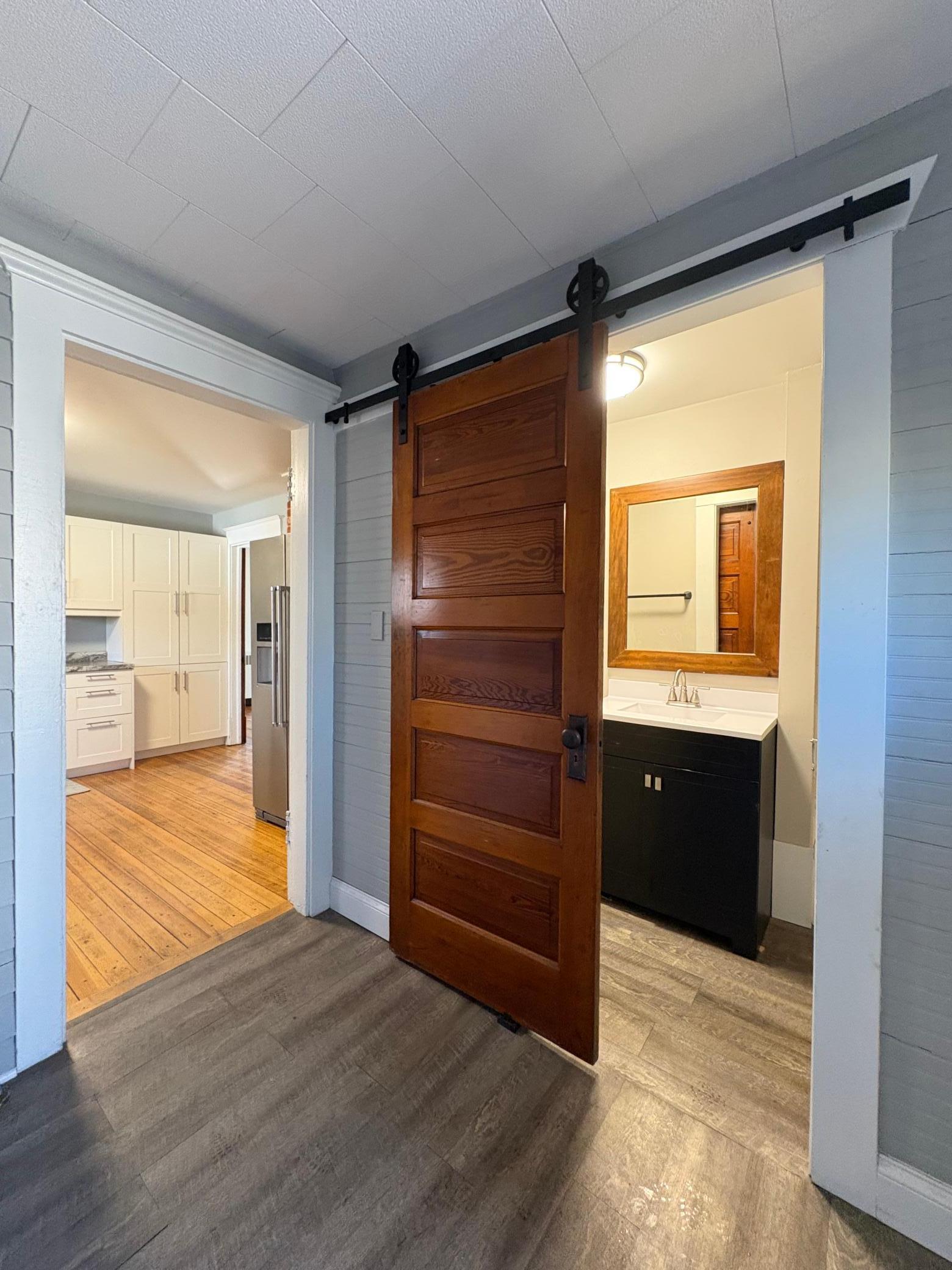back entry laundry room with barn door to full bath on main level.jpeg