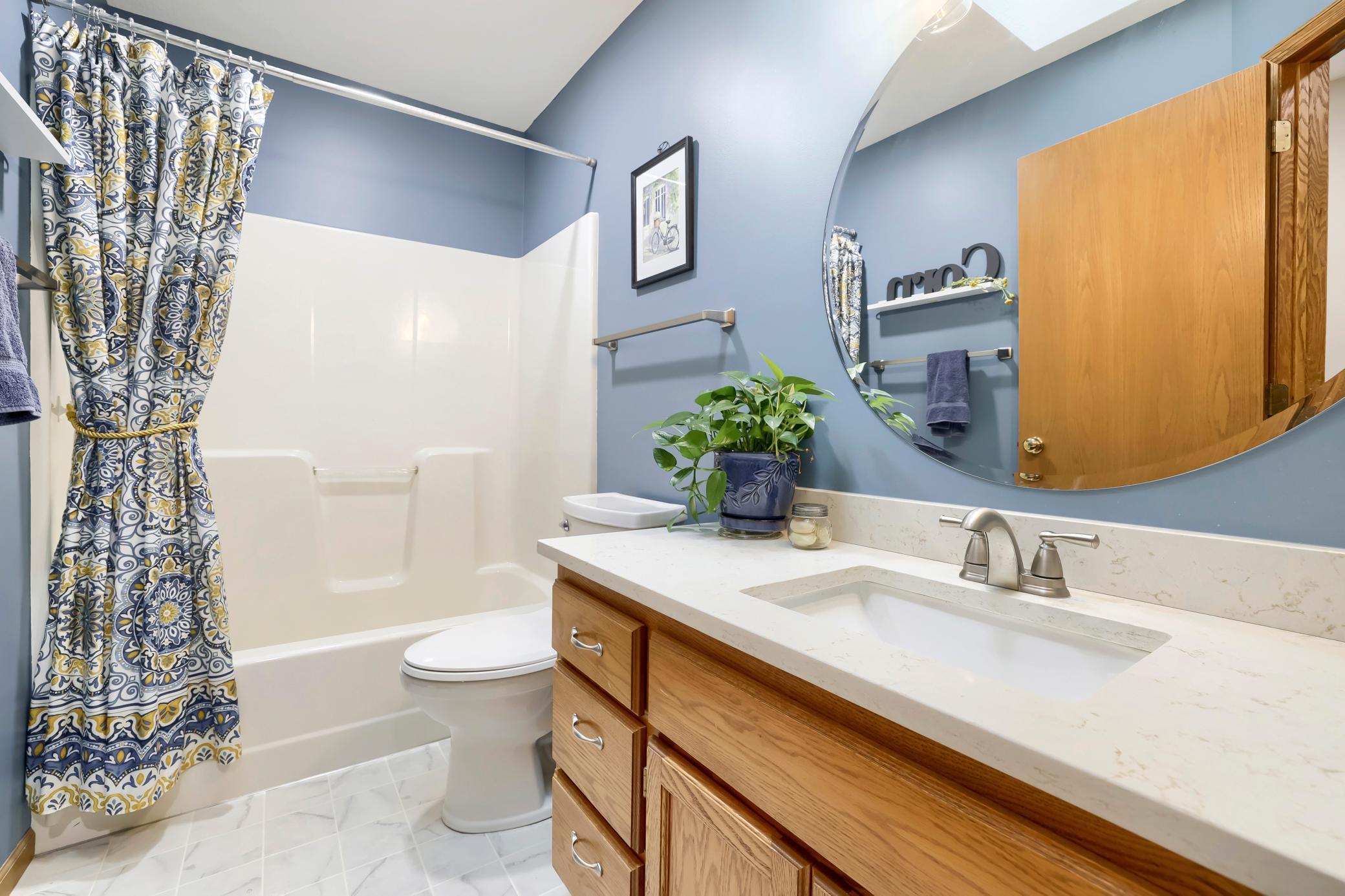 The upper level full bath features quartz countertops and newer fixtures